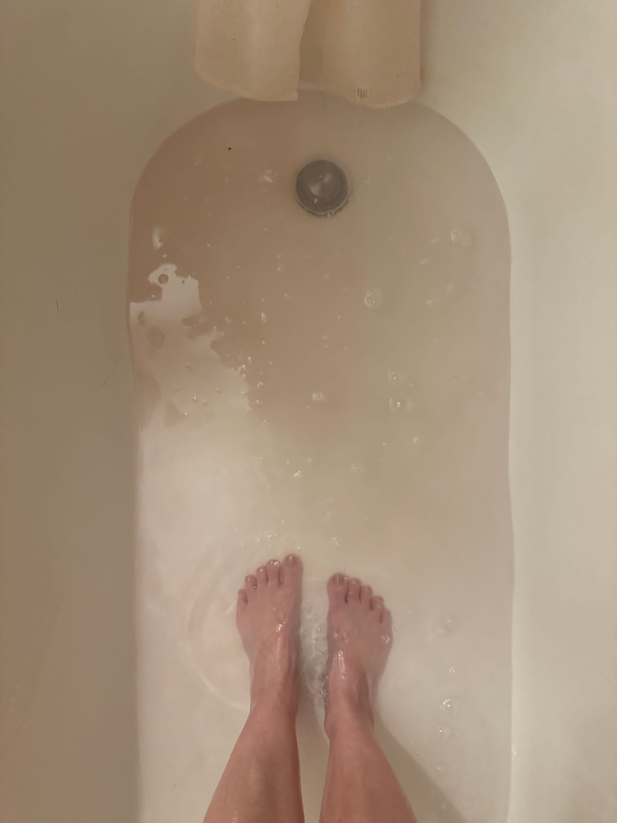 a photo taken in the bath of my feet as the water, tinged with blood to a very light pink, drains away.
